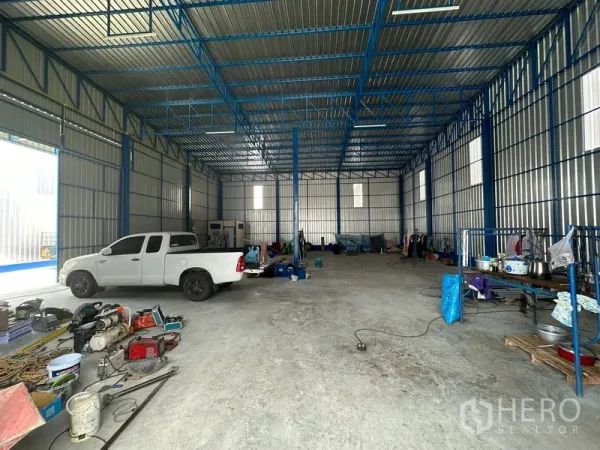 Warehouse for rent in Wang Thonglang, Bangkok - Large high-ceiling warehouse interior with blue steel frame, smooth concrete floor, and open storage space.