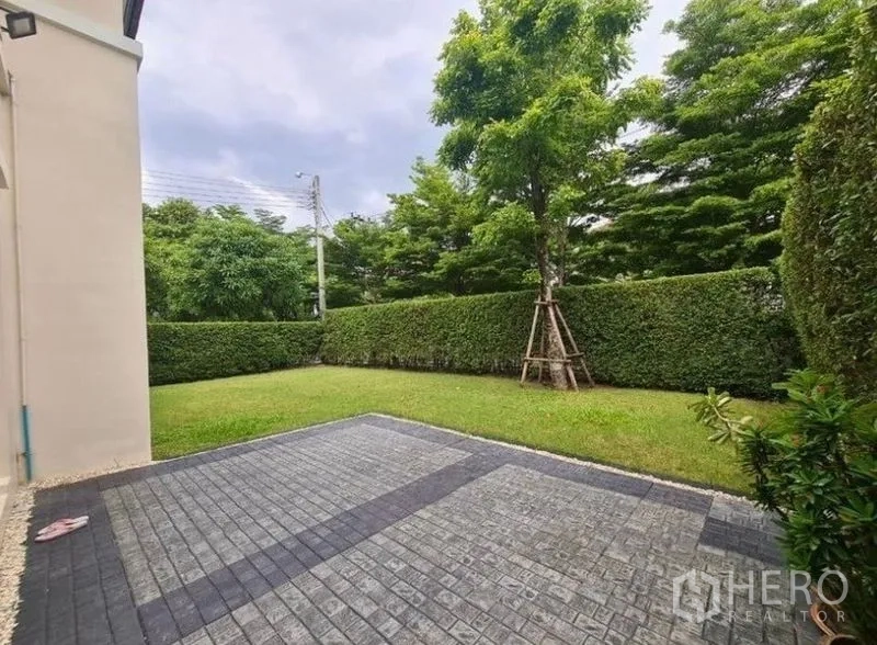 บ้าน ให้เช่าหรือขายในLat Krabang, Bangkok - สวนด้านข้างมีลานปูกระเบื้อง รั้วพุ่มไม้และต้นไม้ ให้ความเป็นส่วนตัว