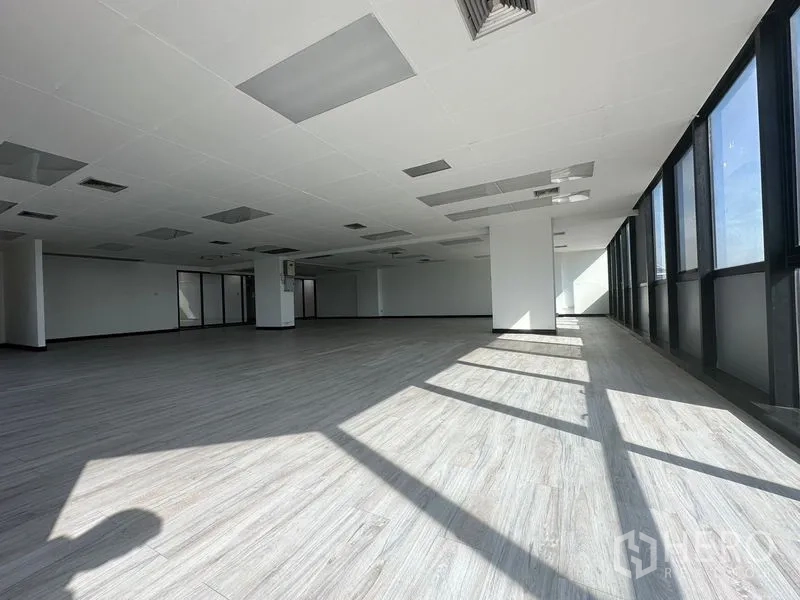 办公空间 出租或出售 - 采光充足的转角办公室，阳光透过高窗洒入，灰色木纹地板。