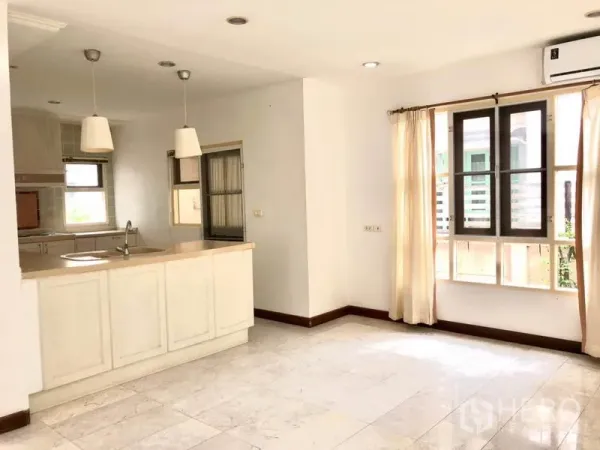 Detached House for rent in Saphan Sung, Bangkok - Bright kitchen with white cabinets, breakfast counter, pendant lights and windows.