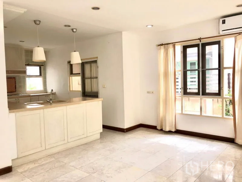 Detached House for rent in Saphan Sung, Bangkok - Bright kitchen with white cabinets, breakfast counter, pendant lights and windows.