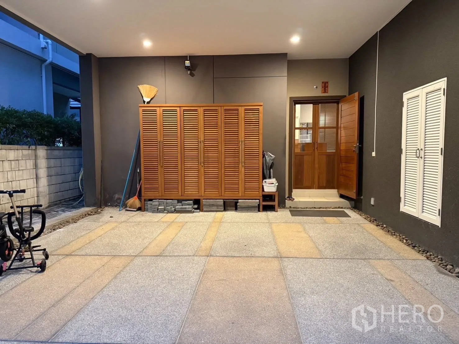 Detached House for rent in Bang Na, Bangkok - Covered carport with lighting and wooden storage cabinet beside an entry door.