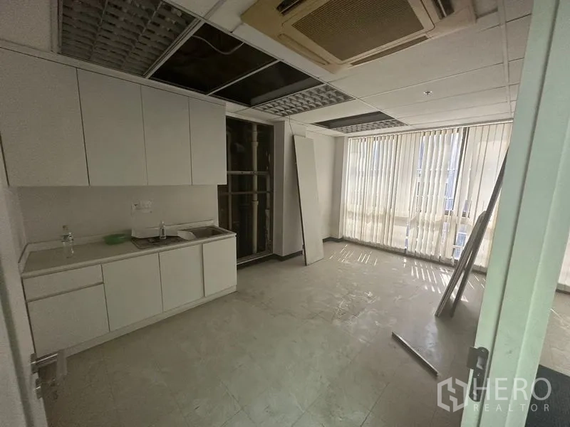 办公空间 出租在Khlong Toei, Bangkok - 办公室茶水间，白色橱柜与水槽，瓷砖地面，吊顶及竖百叶窗。