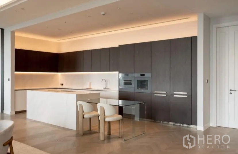 公寓 出租或出售在Pathum Wan, Bangkok - 整面厨房墙体，通顶收纳柜、嵌入式烤箱与玻璃早餐桌。
