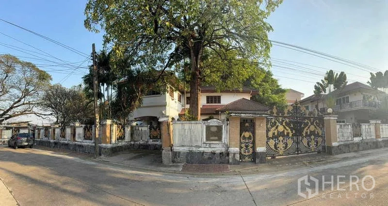 บ้าน ขายในSai Mai, Bangkok - มุมมองแปลงหัวมุม บ้านพร้อมกำแพงรอบ พรางด้วยต้นไม้ใหญ่ และประตูสีดำทองโดดเด่น