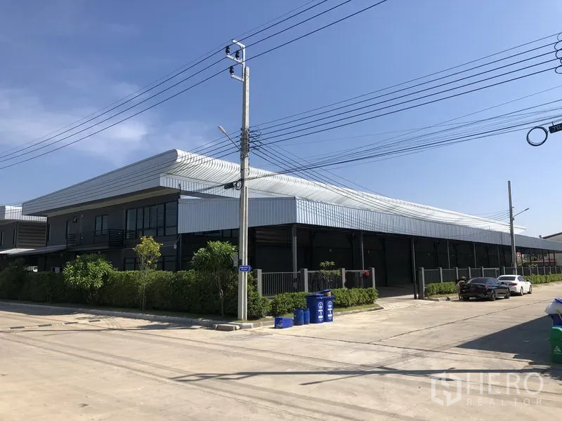 工厂 出租或出售在Bang Bo, Samut Prakan - 转角视角的现代钢结构工厂，临宽阔混凝土道路与停车区。