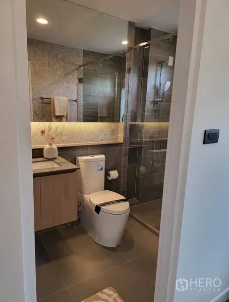 Detached House for rent in Bang Kapi, Bangkok - Contemporary bathroom with glass-enclosed shower, backlit vanity and toilet.