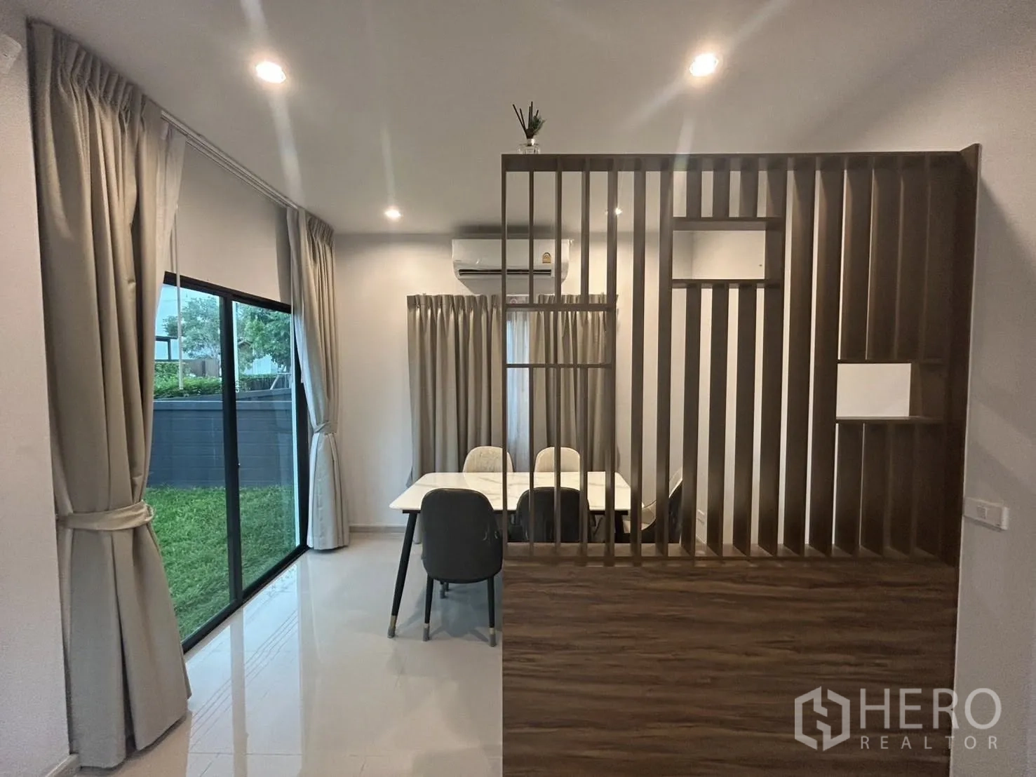 Detached House for rent in Khlong Sam Wa, Bangkok - Open-plan dining area with wood slat partition, large windows and a garden view.