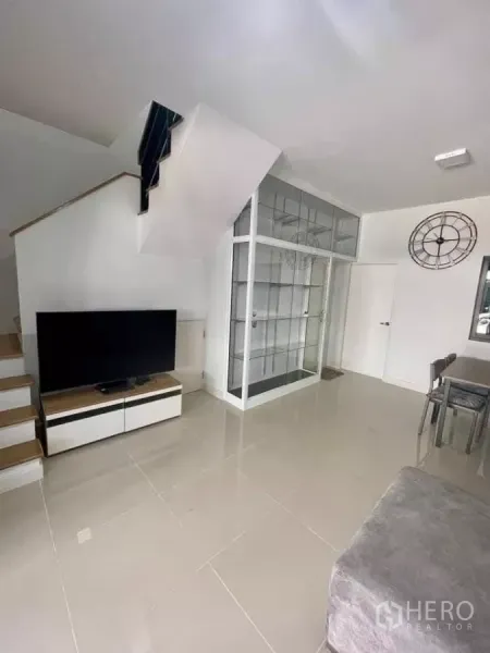 Townhouse for rent in Bang Phli, Samut Prakan - Living room corner with TV console, glass display cabinet and stairs.