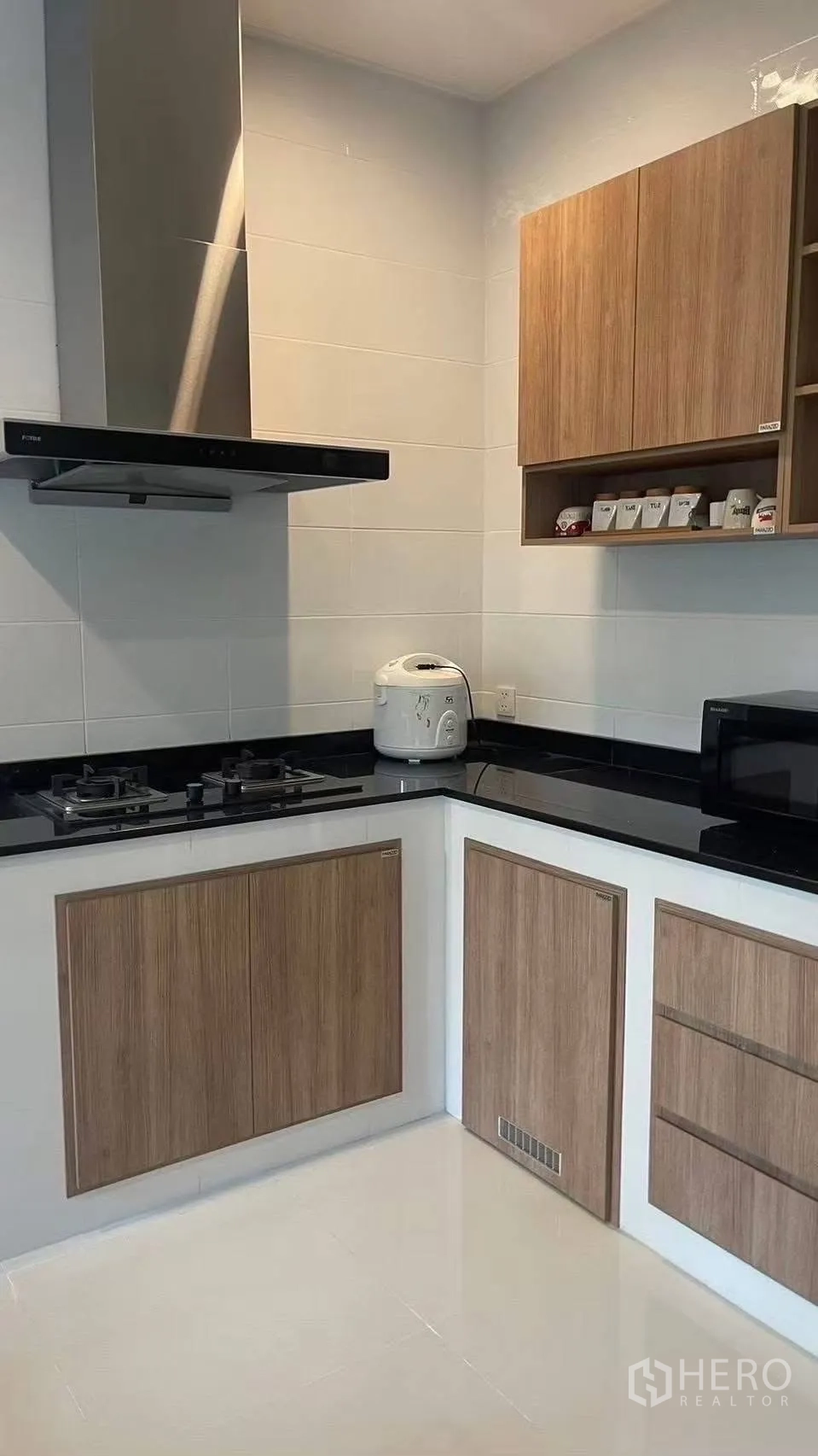 Detached House for rent in Prawet, Bangkok - Modern corner kitchen with gas hob, range hood and wood cabinets.