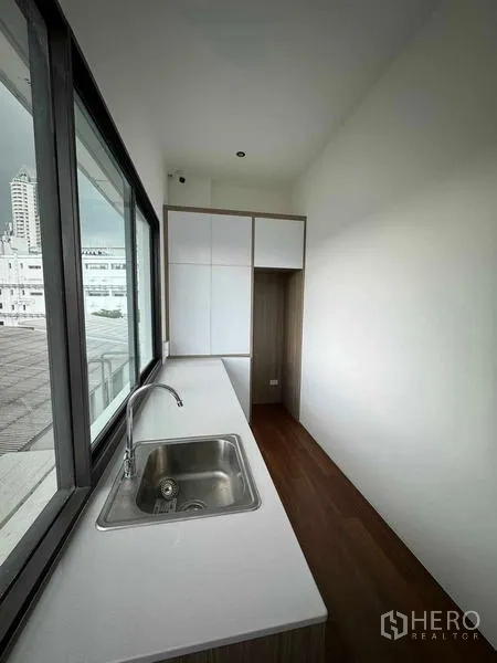 Home Office for rent or sale in Bang Phli, Samut Prakan - Compact pantry with sink, long countertop and upper cabinets by a window.