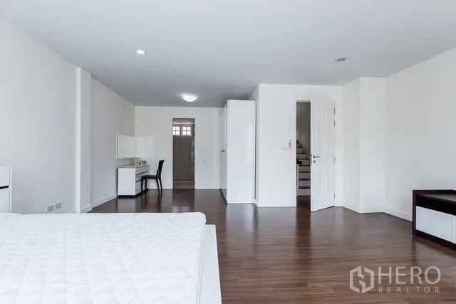 Townhouse for rent in Watthana, Bangkok - Large master bedroom with wood flooring, desk, wardrobes and access to ensuite.