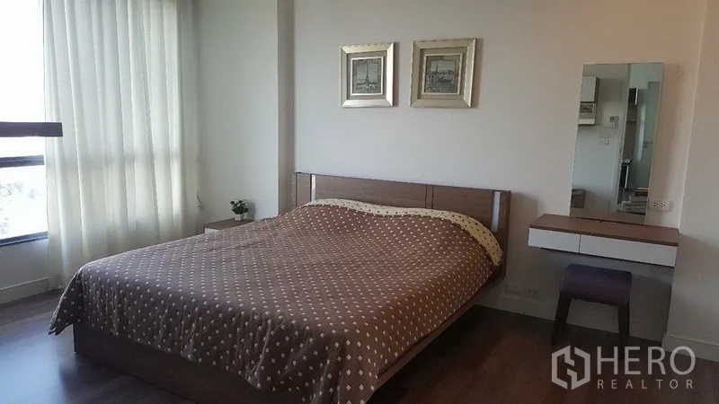 คอนโด ให้เช่าในBangkok - ห้องนอนใหญ่เตียงคิงไซซ์ ผ้าปูสีน้ำตาล จุดวางของข้างเตียง และหน้าต่างบานใหญ่