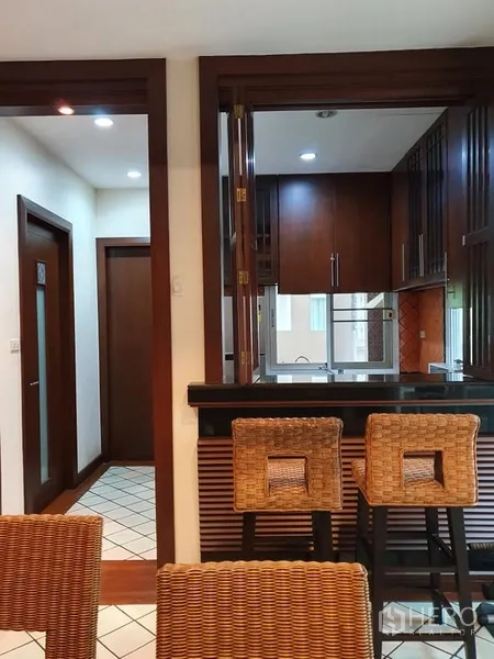 Detached House for rent in Wang Thonglang, Bangkok - Fitted kitchen with pass-through window, black countertop breakfast bar, wooden cabinets and bar stools.
