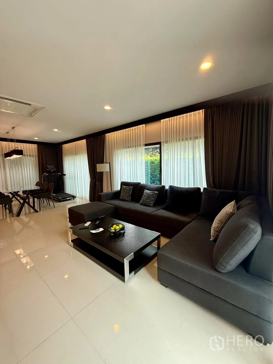 Detached House for rent in Bang Kapi, Bangkok - Spacious lounge with L-shaped sofa, coffee table and full-height sheer curtains.