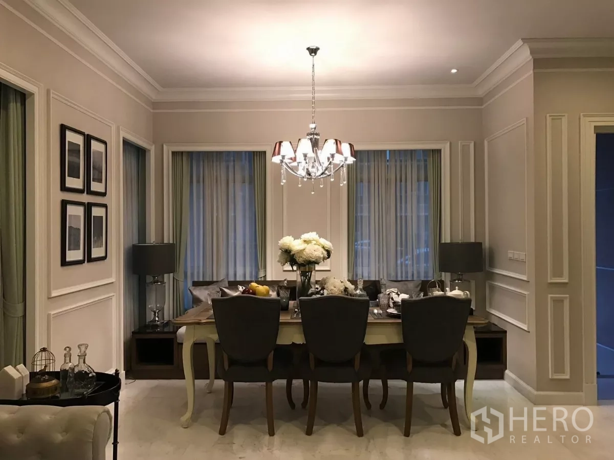 Townhouse for sale in Watthana, Bangkok - Elegant dining room with chandelier, classic wall molding and curtained windows.