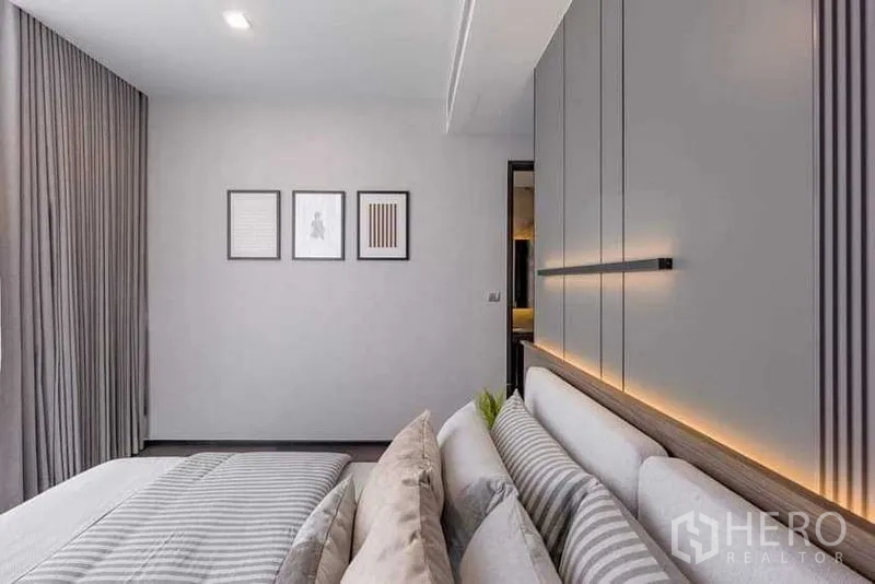 คอนโด ให้เช่า - ผนังห้องนอนติดกรอบภาพ และผ้าม่านสูงจรดเพดานฝั่งตรงข้ามเตียง