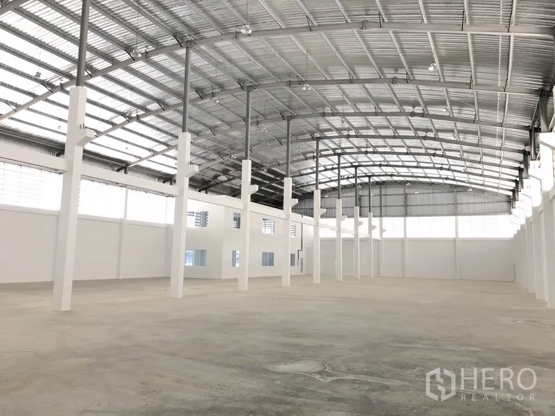 Warehouse for rent in Samut Prakan - Spacious warehouse interior with high arched steel roof, skylights, and open column layout.