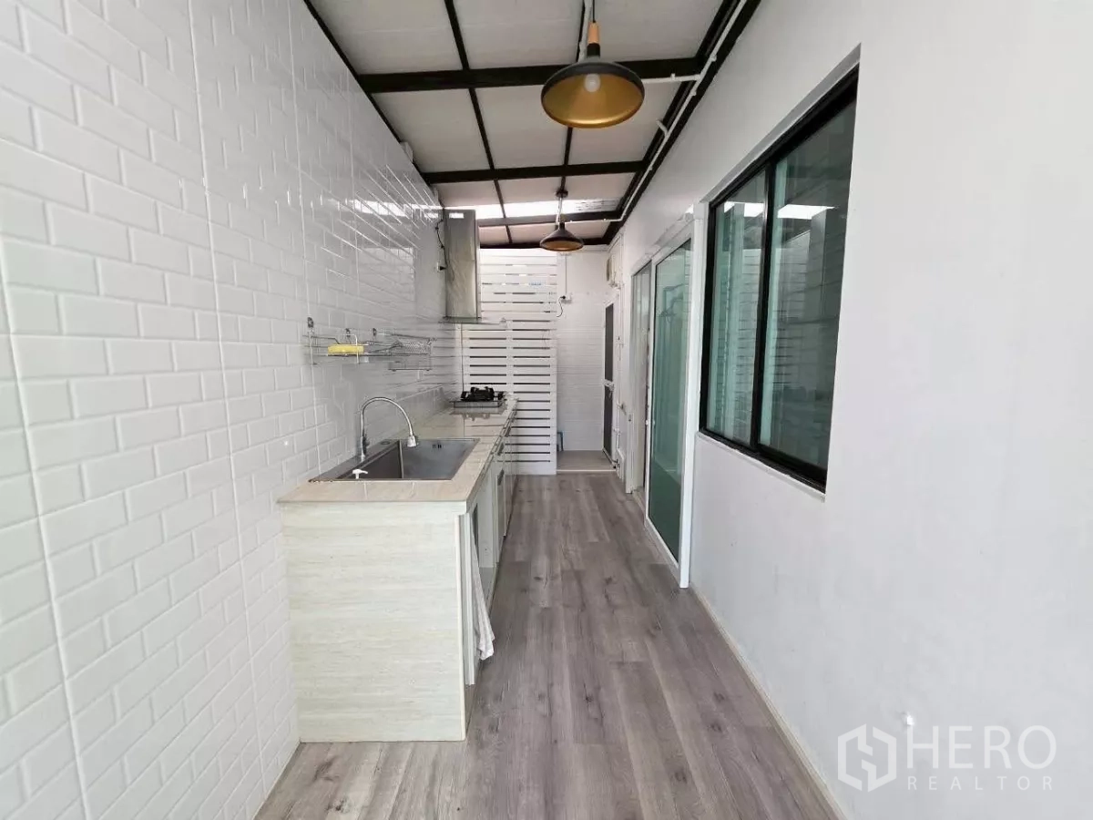 Detached House for rent or sale in Samut Prakan - Long Thai kitchen corridor with pendant lights and sliding door access.