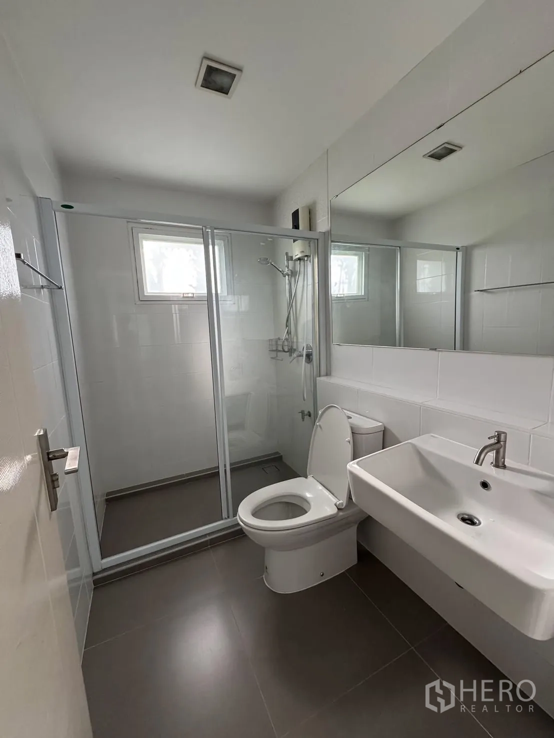 Detached House for rent in Bang Phli, Samut Prakan - Bathroom with glass-enclosed shower, toilet and wall-mounted sink.