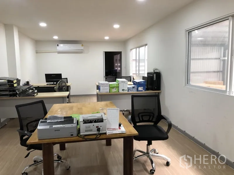 Warehouse for rent in Nonthaburi - Open-plan office workspace with meeting table, windows and LED downlights.