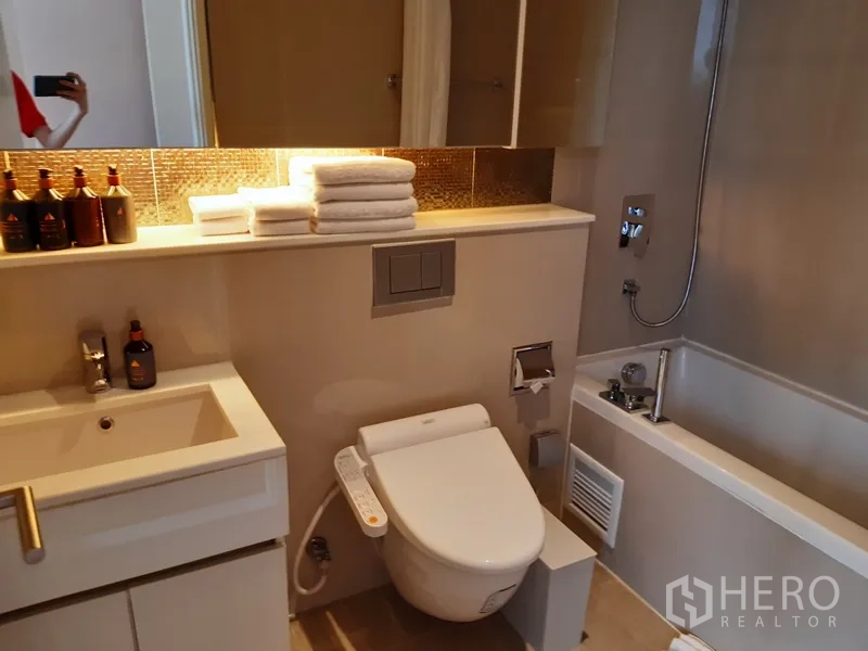 Condominium for rent in Watthana, Bangkok - Bathroom with bathtub, bidet toilet and illuminated mirror shelf.