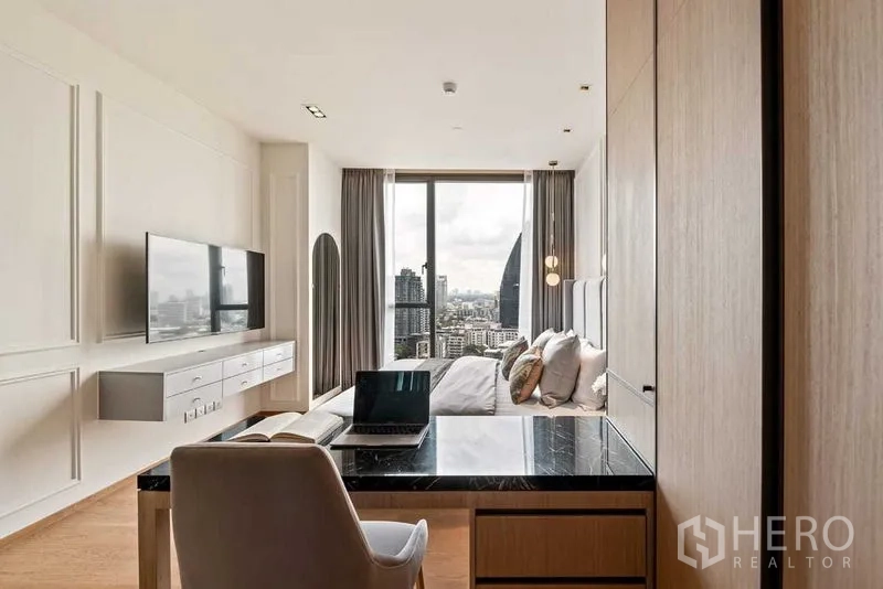 公寓 出租或出售在Khlong Toei, Bangkok - 卧室带学习桌、壁挂电视与窗外城市景观。