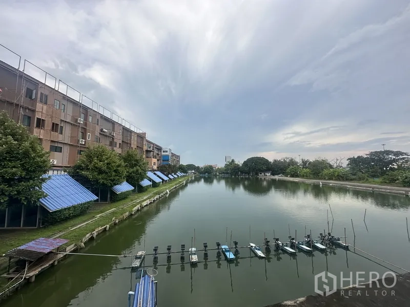 独立商业地产 出租在Prawet, Bangkok - 大型鱼塘/湖景，两侧建筑与树木，阴天