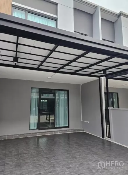 Townhouse for rent in Bang Phli, Samut Prakan - Modern two-storey townhouse facade with covered carport and sliding glass door.