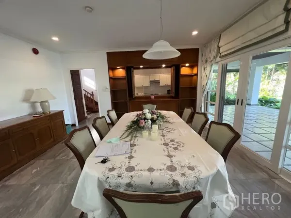 Detached House for rent in Bang Phli, Samut Prakan - Formal dining room for eight with wood built-ins, pass-through to the kitchen, and sliding doors to the terrace.