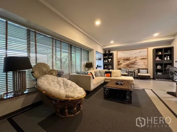 Townhouse for rent or sale in Bang Phli, Samut Prakan - Cozy lounge with long window blinds, artwork, shelving and warm ambient lighting.