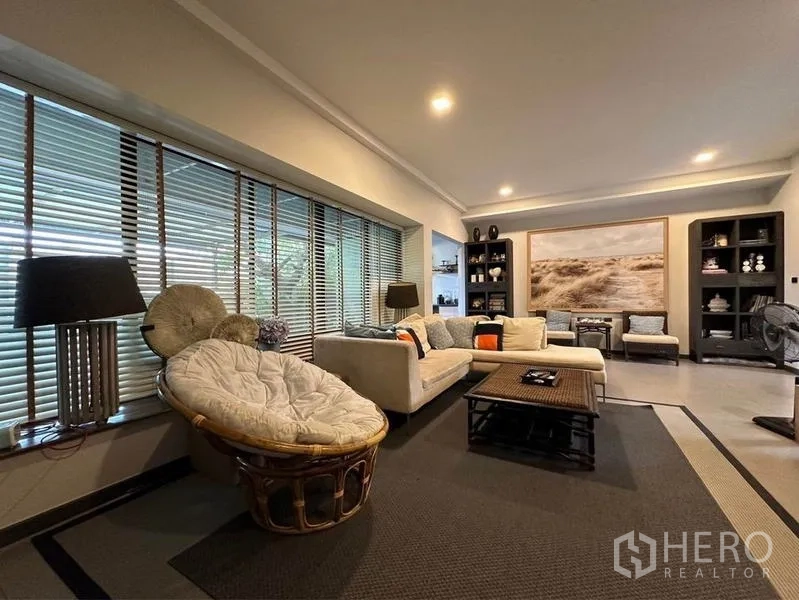 Townhouse for rent or sale in Bang Phli, Samut Prakan - Cozy lounge with long window blinds, artwork, shelving and warm ambient lighting.
