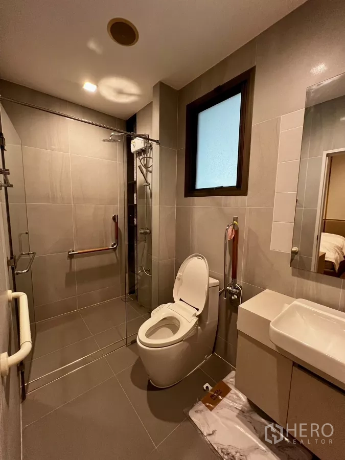 Detached House for rent or sale in Prawet, Bangkok - Bathroom with glass shower cabin, toilet and safety grab bars.