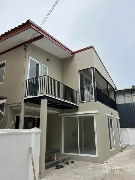 Detached House for rent in Huai Khwang, Bangkok - Two-storey detached house exterior in Huai Khwang with balcony, large windows and sliding glass doors.