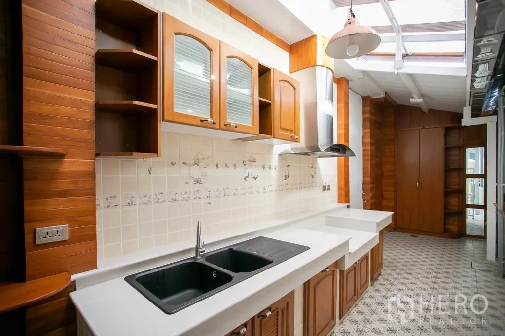 Detached House for rent or sale in Huai Khwang, Bangkok - Kitchen with wooden cabinets, range hood and long counters under skylight.