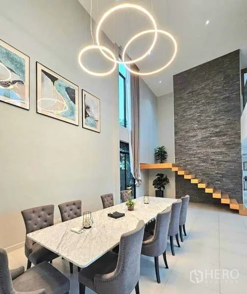 บ้าน ขายในKhlong Sam Wa, Bangkok - ห้องรับประทานอาหารหรู โต๊ะหินอ่อนยาว เก้าอี้บุนวม และผนังบันไดลอย