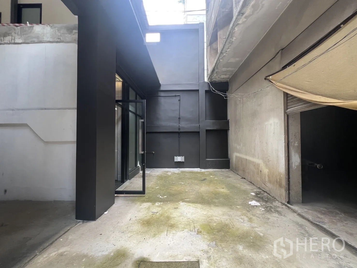店屋 for rent in Bang Rak, Bangkok - 小院视角，黑色立面与开启的玻璃入口。