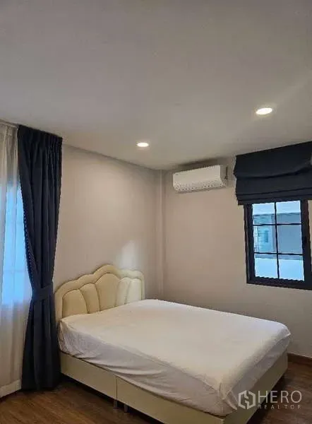 Detached House for rent in Bang Phli, Samut Prakan - Cozy bedroom with upholstered bed, air-conditioner and dark drapes by the window.
