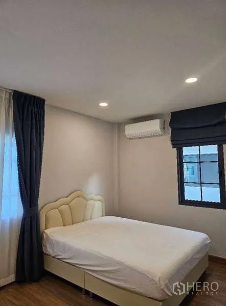 Detached House for rent in Bang Phli, Samut Prakan - Cozy bedroom with upholstered bed, air-conditioner and dark drapes by the window.