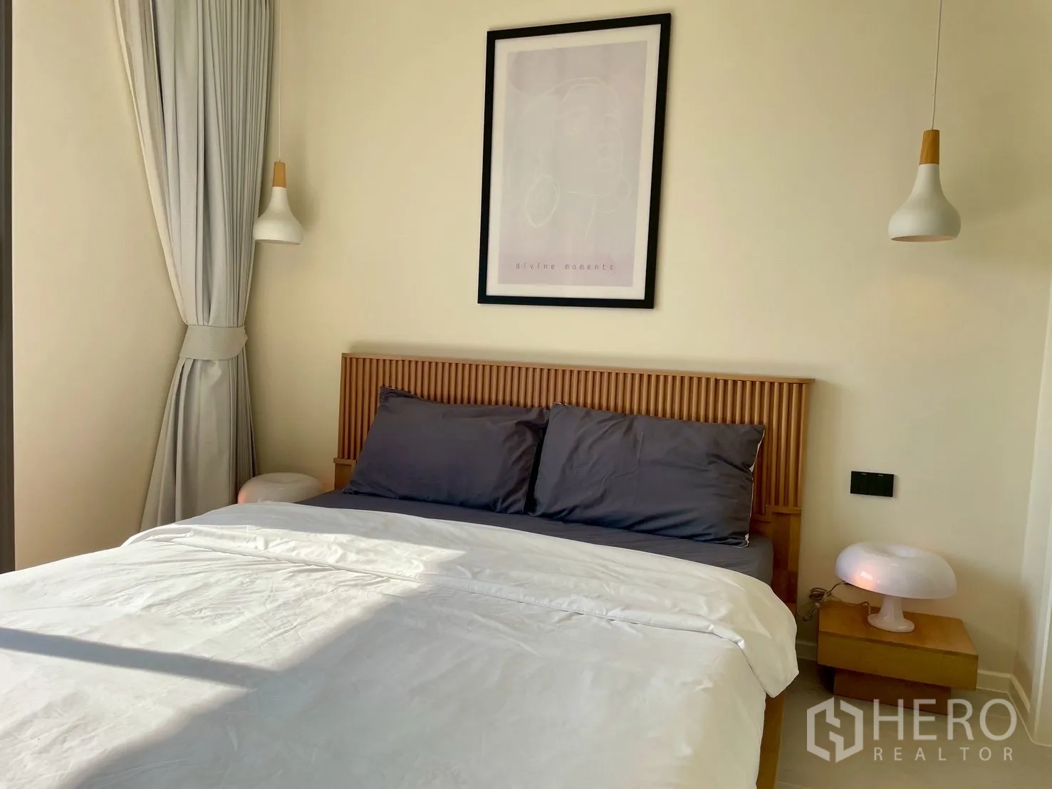 Condominium for sale in Watthana, Bangkok - Bedroom corner with bed, framed art, and pendant bedside lights.