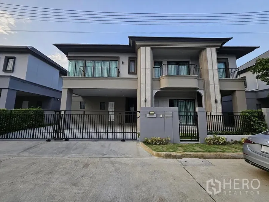 Detached House for sale in Mueang Pathum Thani, Pathum Thani - Modern two-storey detached house with balconies and a gated driveway.