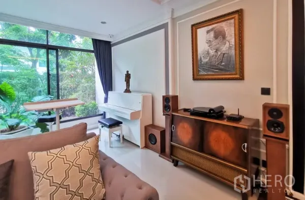 Detached House for rent or sale in Bang Kapi, Bangkok - Cozy music corner featuring a white piano, garden-view window, vintage console and speakers.