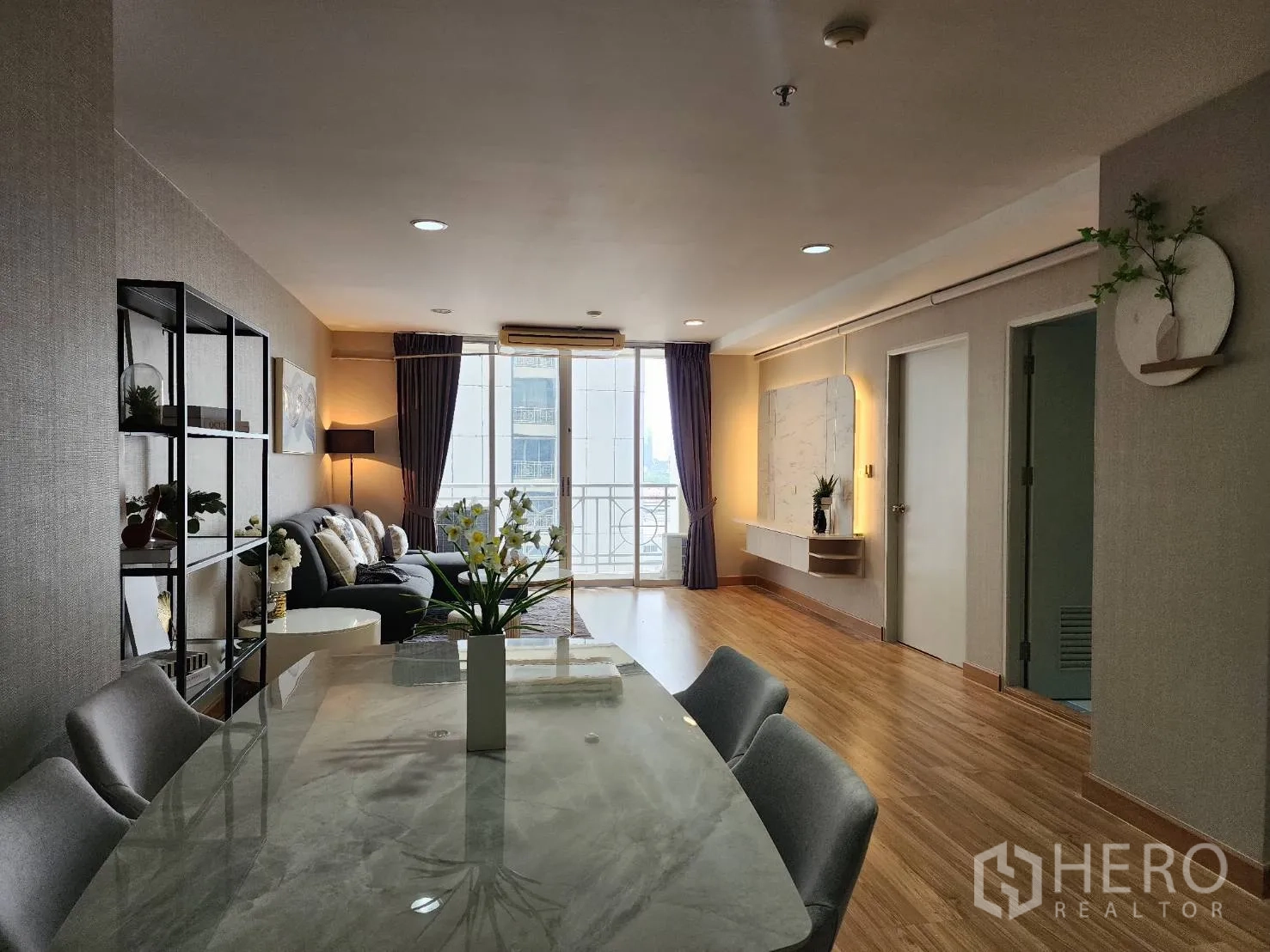 Condominium for rent in Watthana, Bangkok - Open-plan living and dining area with marble-top table and balcony doors.