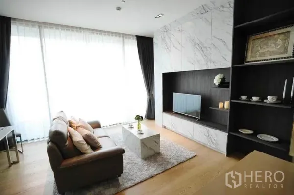 公寓 出租在Bang Rak, Bangkok - 明亮客厅，落地窗、大理石电视墙与皮沙发。