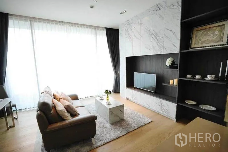 公寓 出租在Bang Rak, Bangkok - 明亮客厅，落地窗、大理石电视墙与皮沙发。