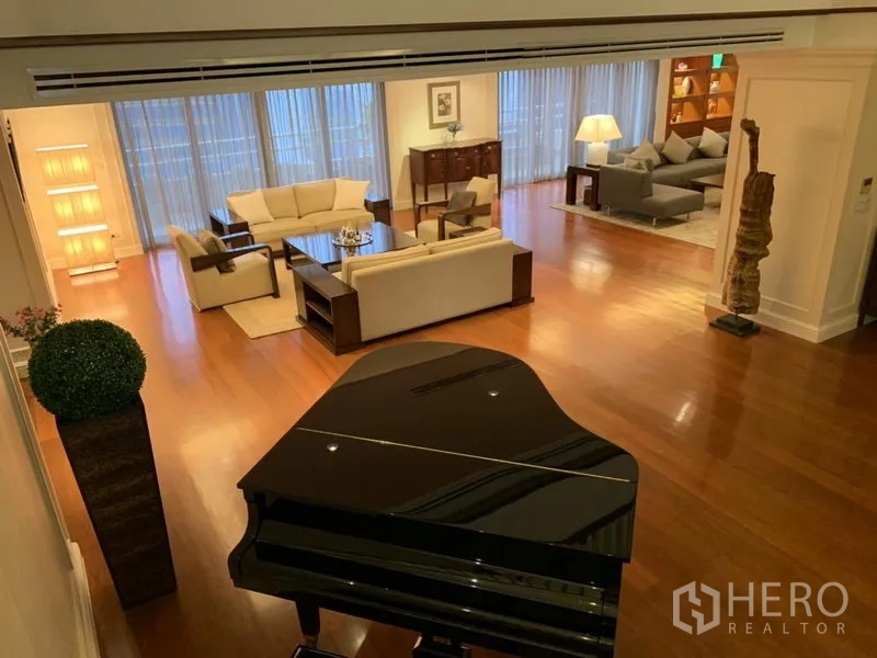 Condominium for rent or sale in Watthana, Bangkok - Expansive living room with hardwood floors, white sofas and a glossy grand piano.