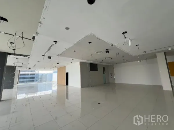 零售空间 出租在Din Daeng, Bangkok - 大型商铺角落，服务核心墙体、瓷砖地面与明亮窗面。