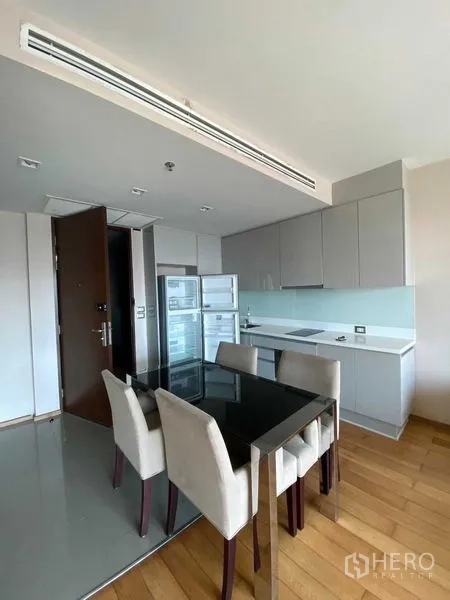 Condominium for sale in Ratchathewi, Bangkok - Open-plan kitchen with grey cabinets, glass backsplash, built-in hob, full-height fridge and a four-seat dining table.