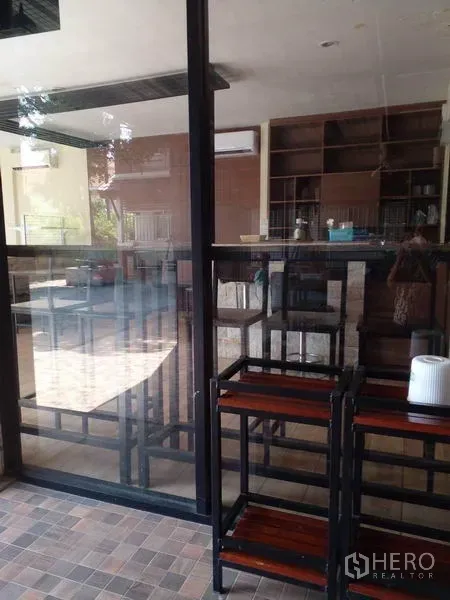 Shophouse for sale in Lam Luk Ka, Pathum Thani - Interior glass wall with shelving and high stools beside the lobby area.
