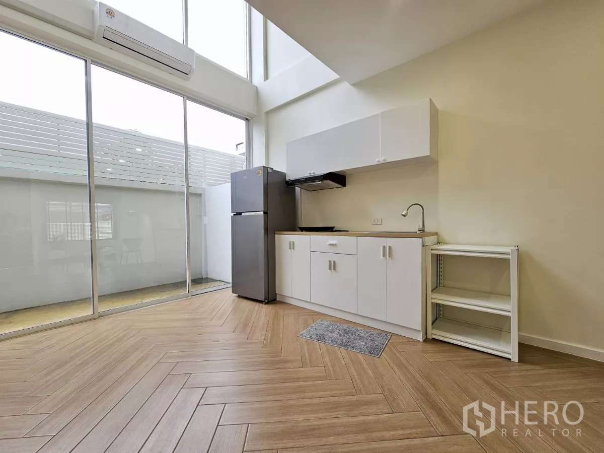 联排别墅 出售在Lat Phrao, Bangkok - 简洁茶水间，通高玻璃墙与人字形木地板，挑高空间